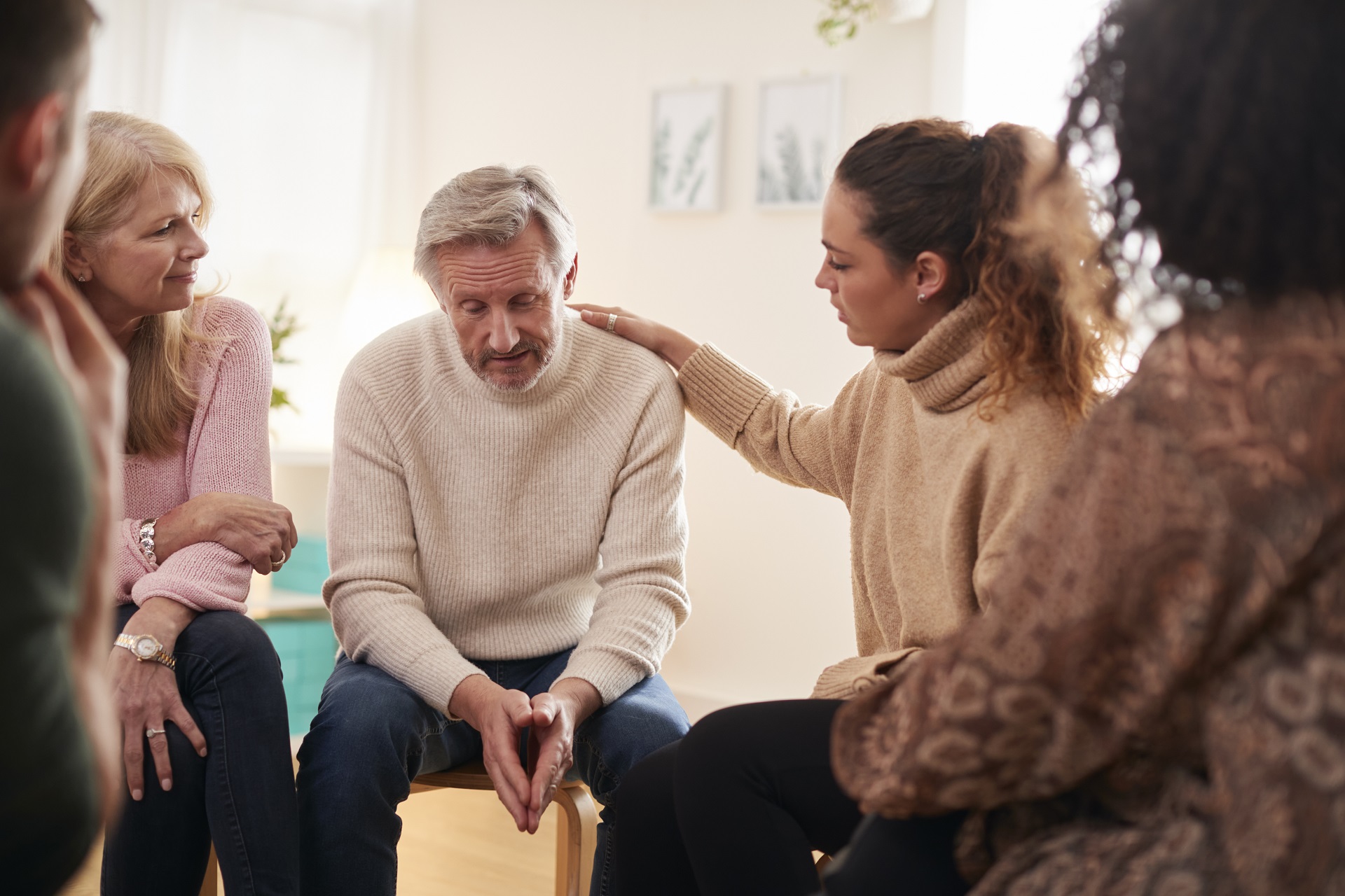 Group Consoling Man Speaking At Support Group Meeting For Mental Health Or Dependency Issues