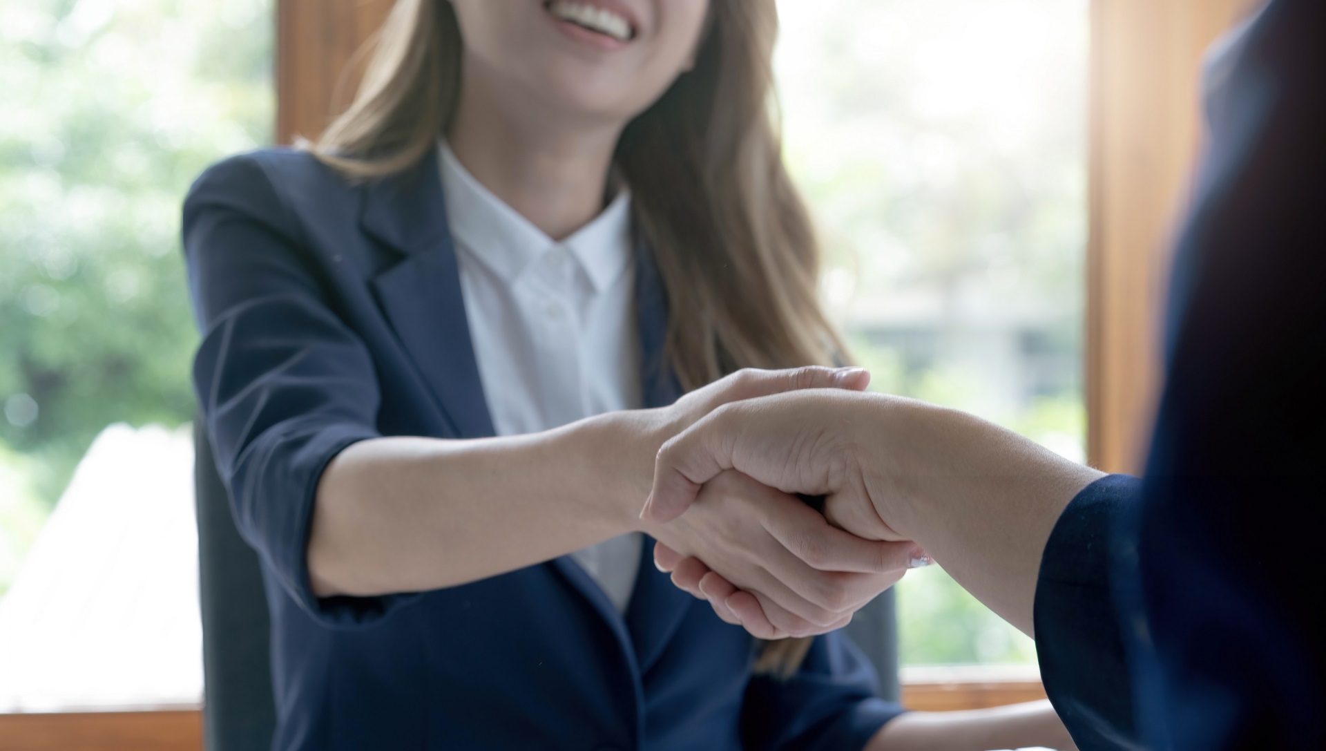 Closeup of unrecognizable happy businesswoman shaking hands with business partner after signing contract during meeting in office.